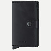 Petit portefeuille en cuir noir vieilli mat, fermé par sa patte à bouton pression