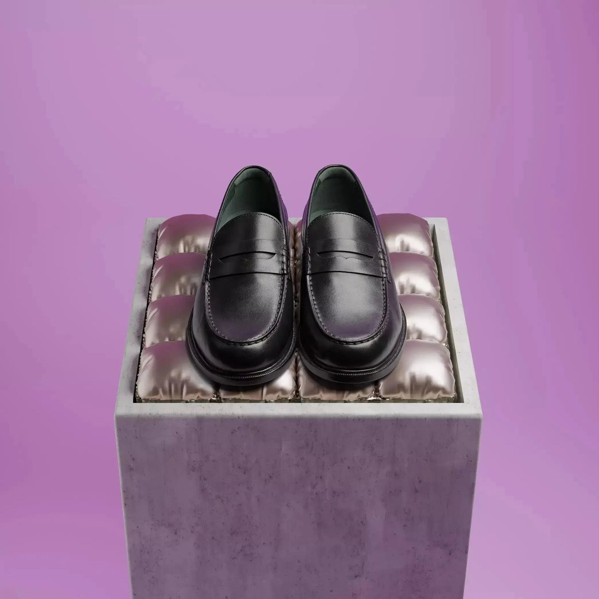 Paire de mocassins Craft James Lo noirs posée sur un socle, fond violet