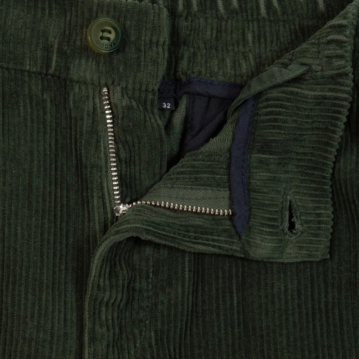 Détail de la braguette zippée du Pantalon Dreuille Faguo, bouton gravé et parementure bleu marine sur velours vert foncé