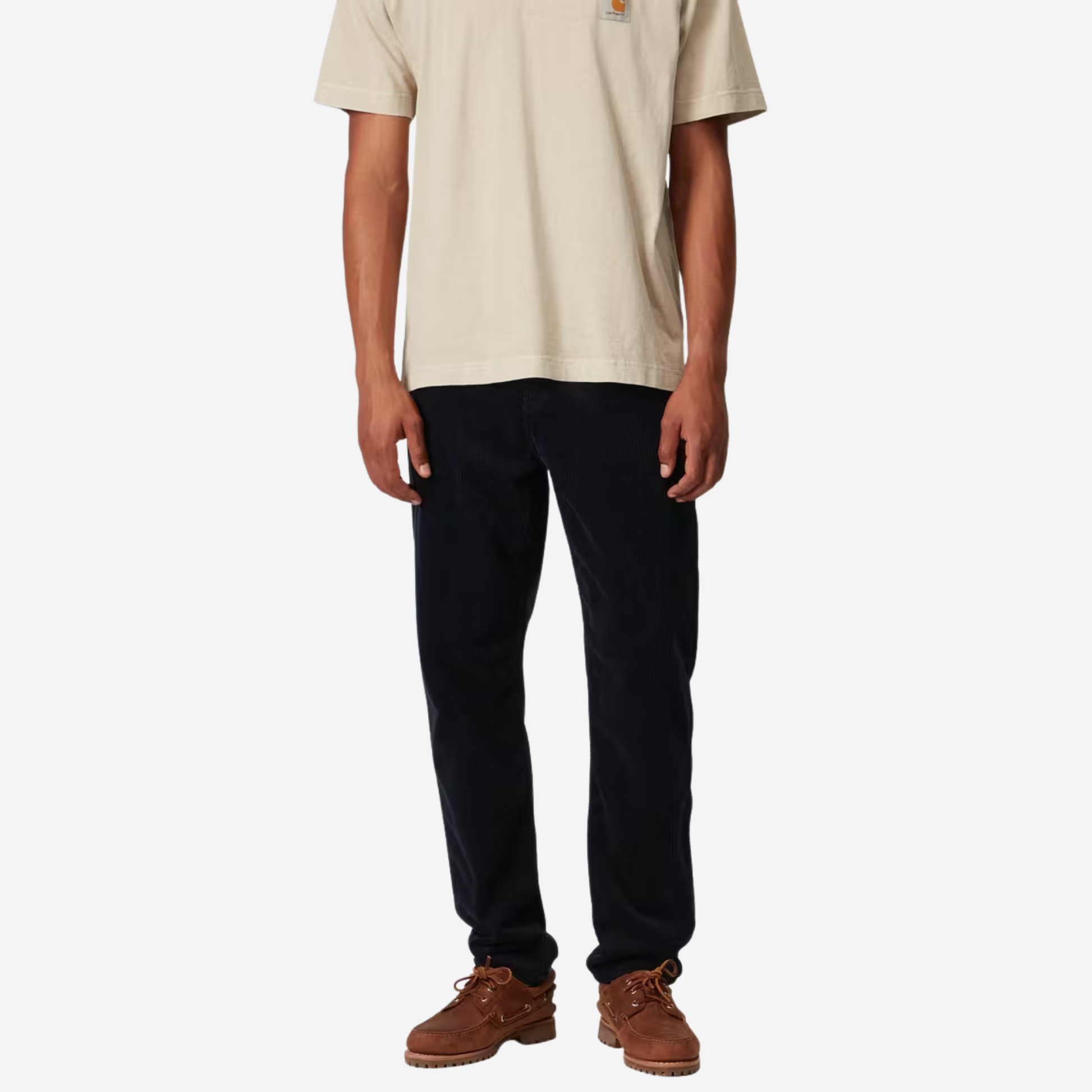 Pantalon Newel velours bleu marine Carhartt WIP porté de face avec un t-shirt écru et des chaussures bateau