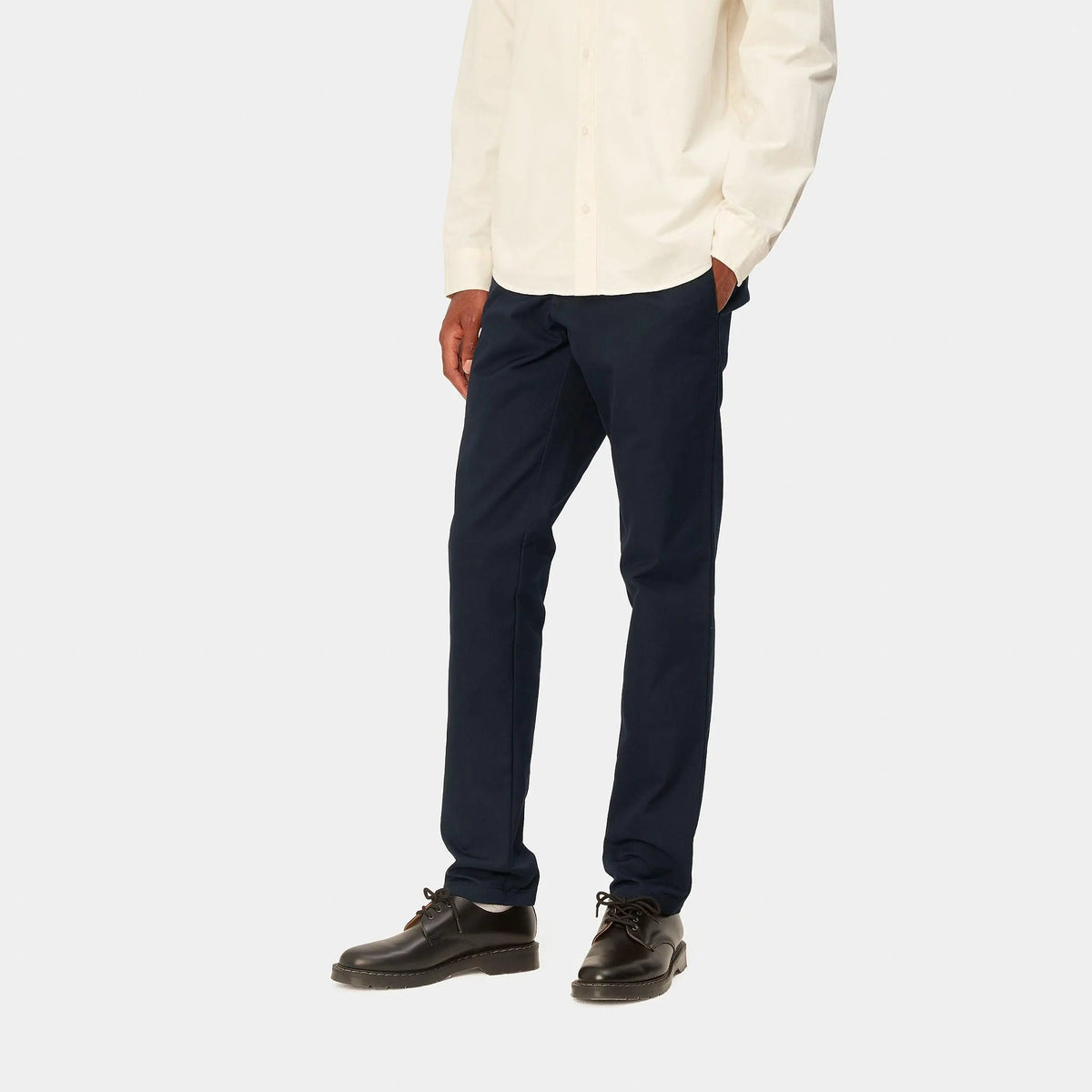 Sid Pant bleu marine porté de trois quarts avec une chemise écrue, tombé net sur des derbies noirs
