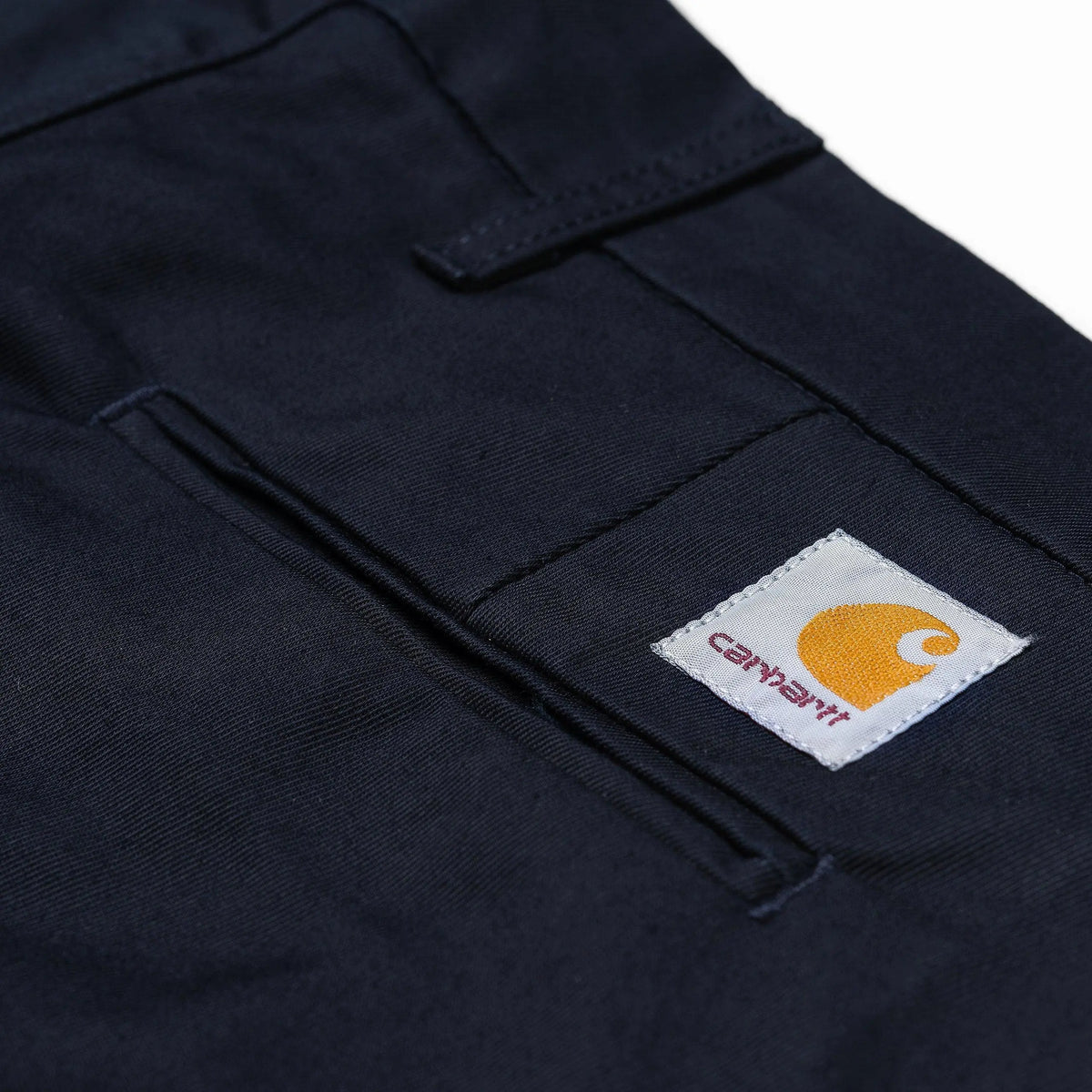 Gros plan sur une poche arrière passepoilée du Sid Pant bleu marine, Square Label tissé cousu à côté