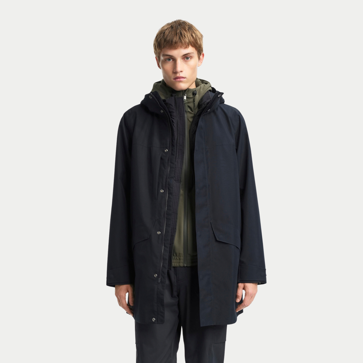 Parka T-KIT noire portée ouverte sur la sous-veste kaki du système T-KIT