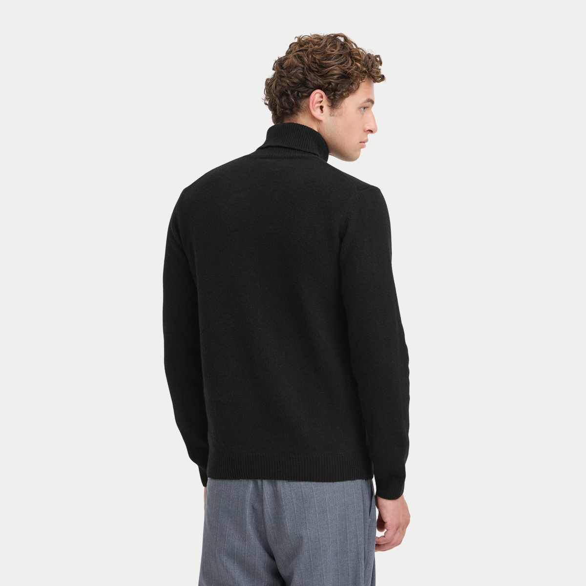 Dos du pull col roulé noir Casual Friday, porté, bas de corps côtelé sur un pantalon gris chiné