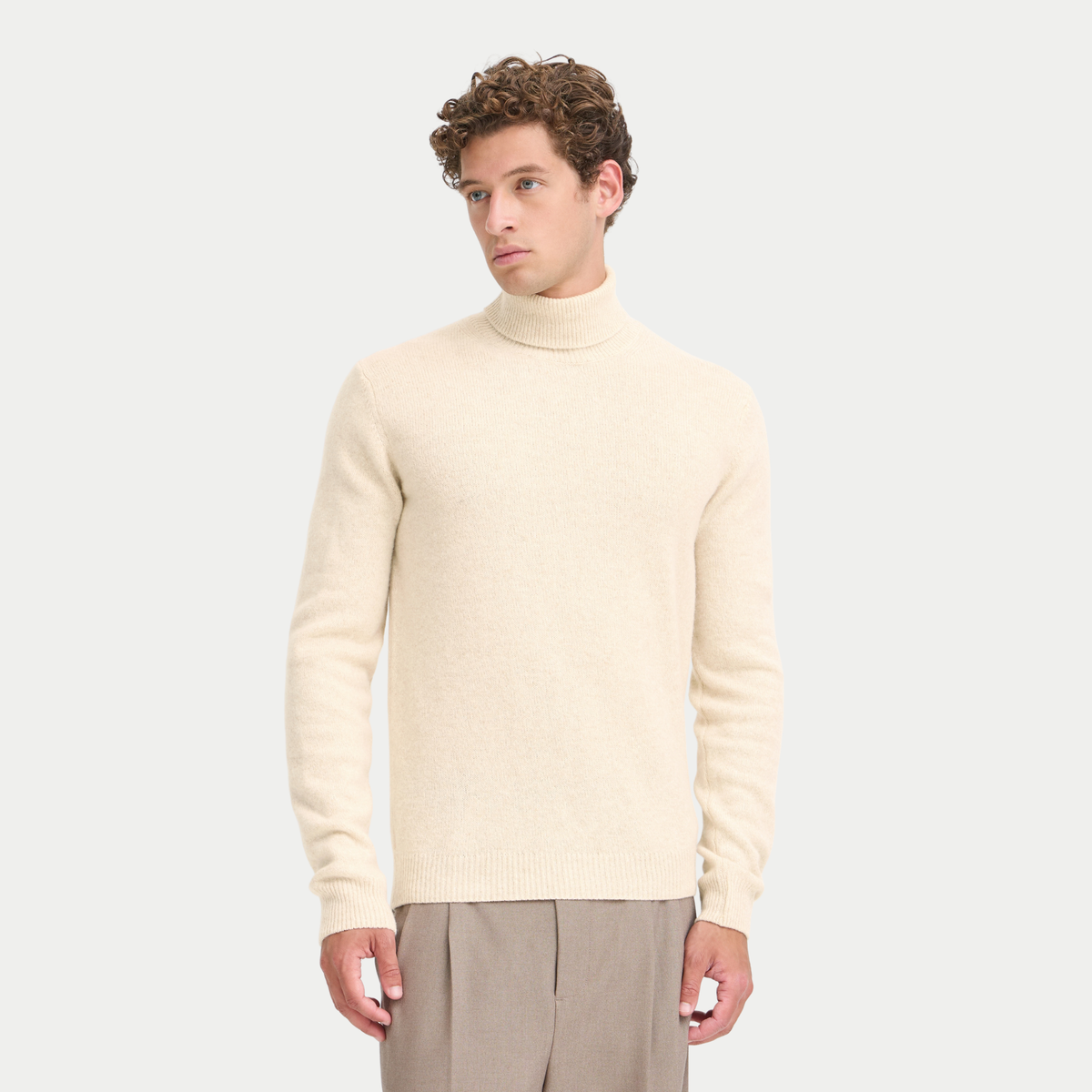 Col roulé écru crème porté de face, maille fine à peine chinée, associé à un pantalon taupe