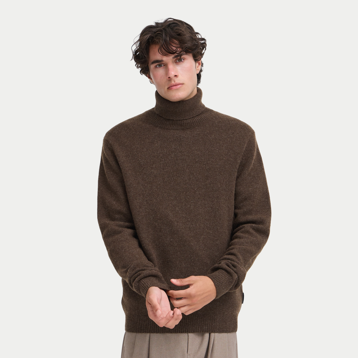 Col roulé brun très sombre chiné porté de face, maille fine en laine d'agneau et pantalon taupe
