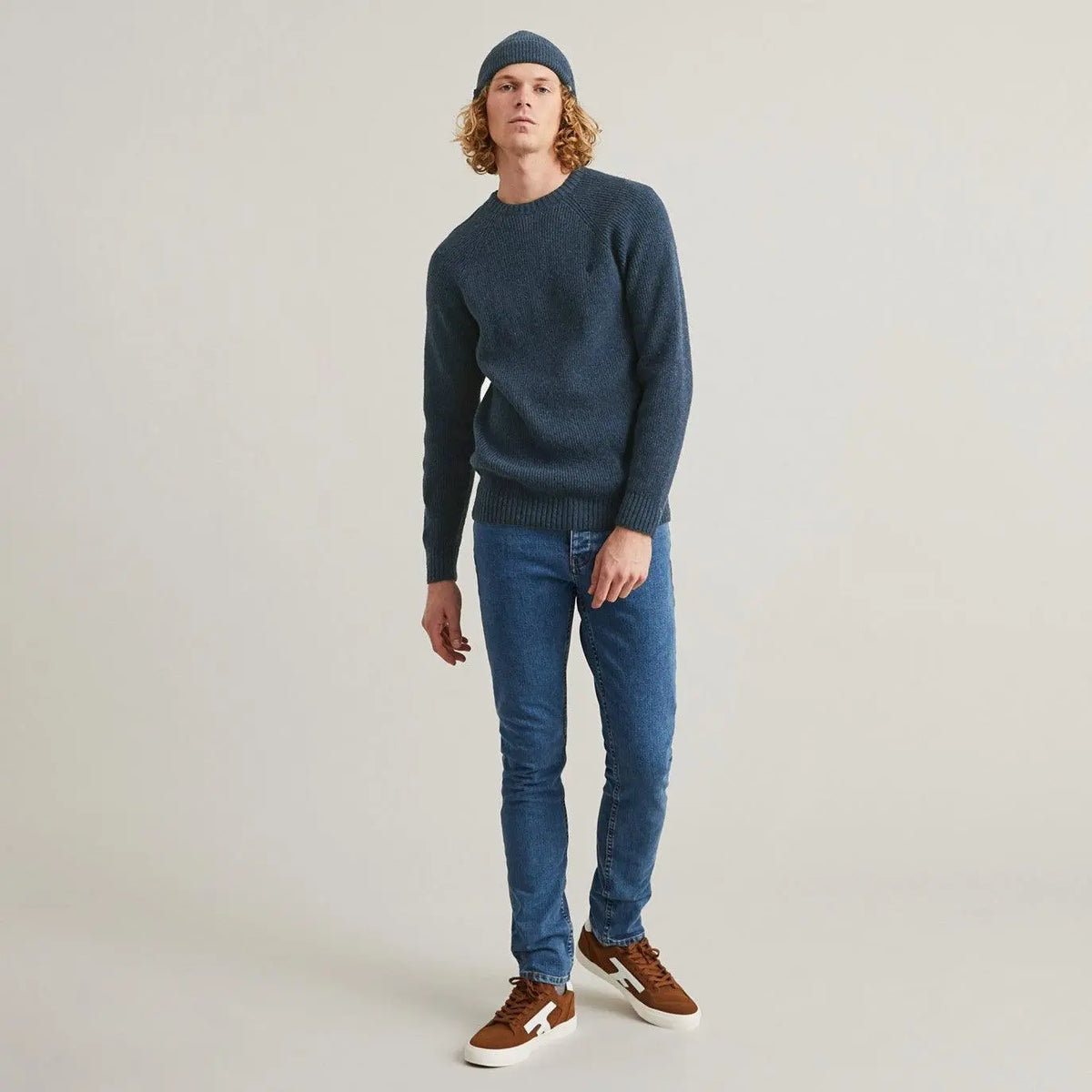 Pull Frehel bleu porté en pied avec un jean brut et un bonnet assorti