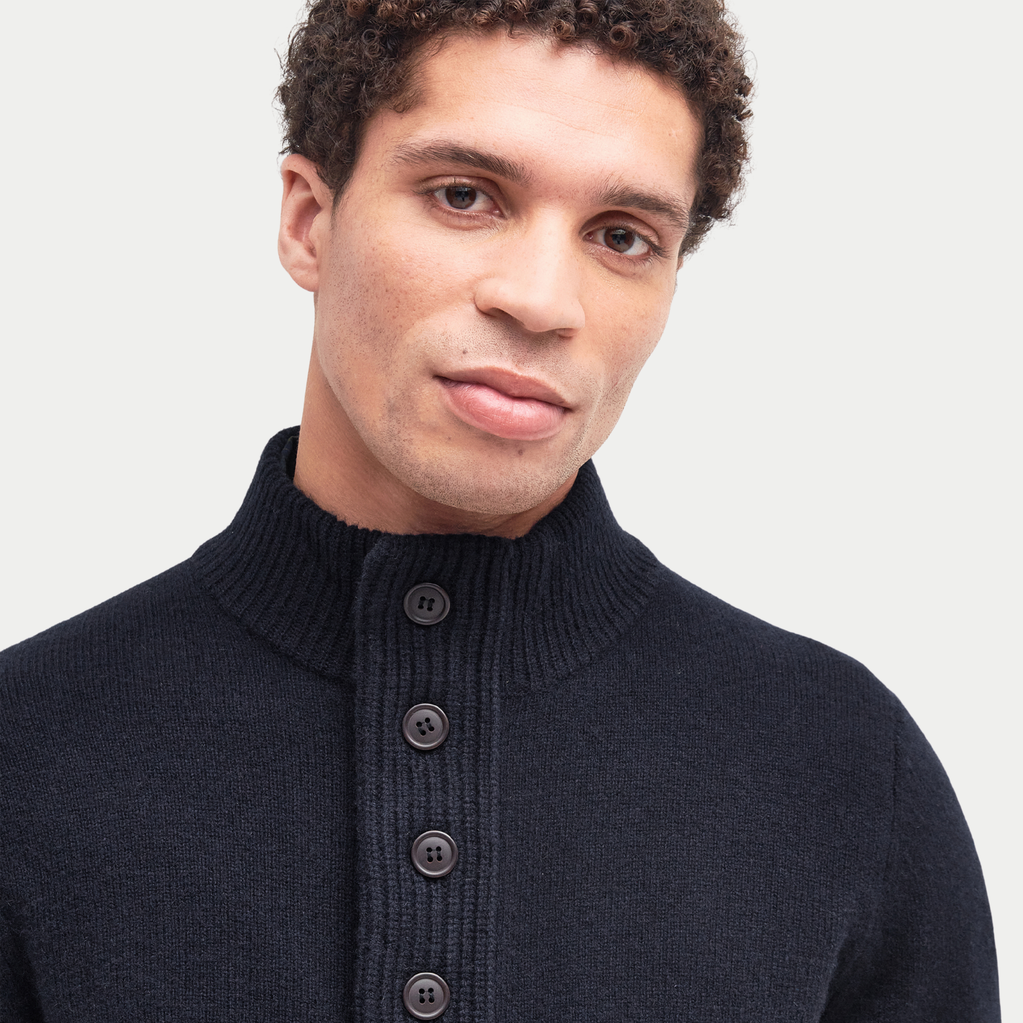 Gros plan du col montant du Pull Barbour Essential Patch bleu marine, patte boutonnée fermée
