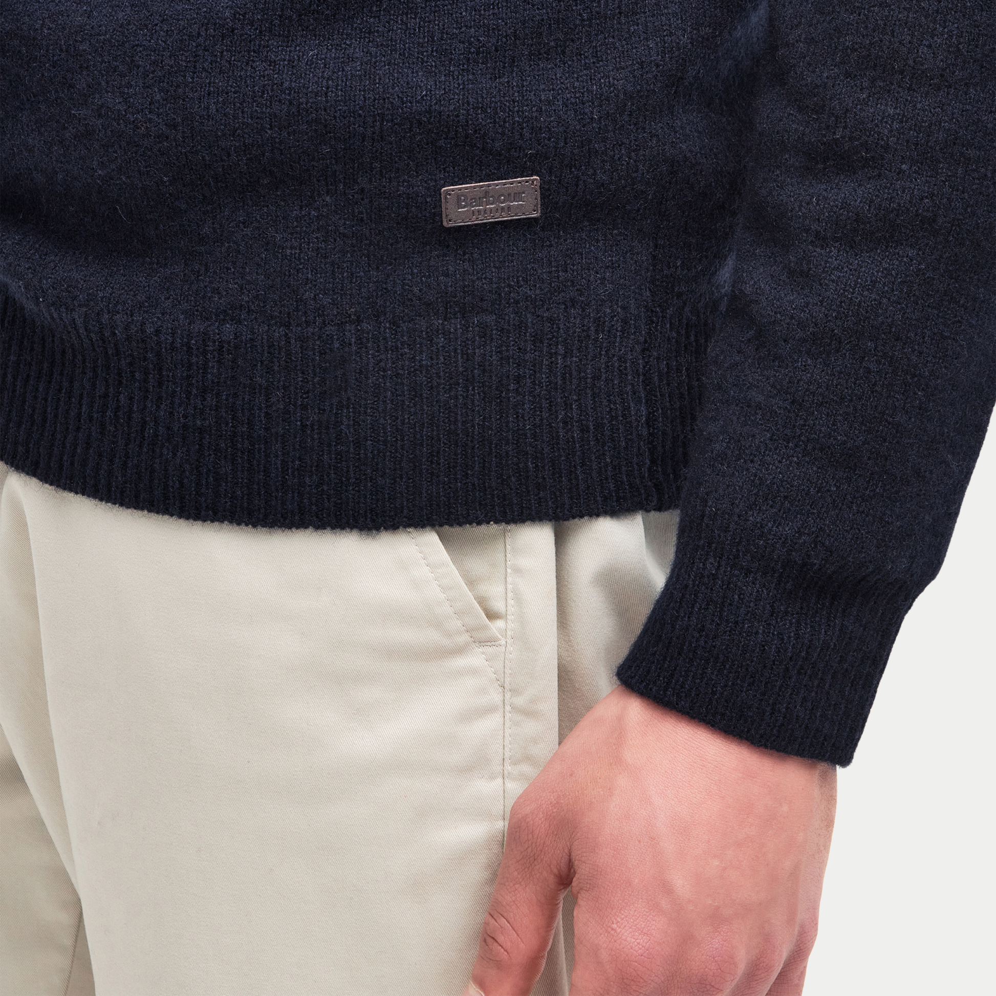 Détail du bas de pièce côtelé du Pull Barbour Essential Patch bleu marine et de sa plaque Barbour