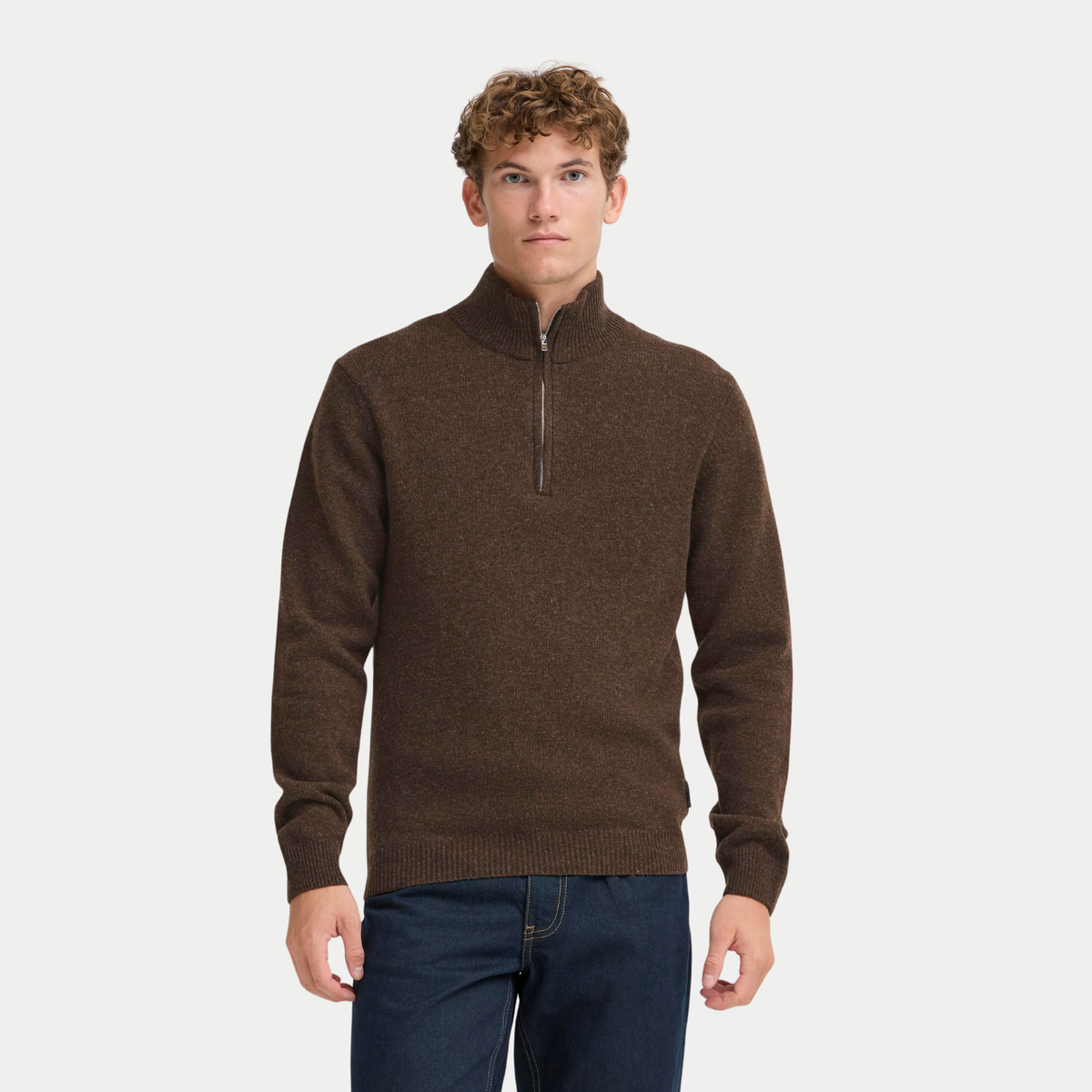 Pull half zip marron foncé porté de face avec un jean brut, col montant fermé