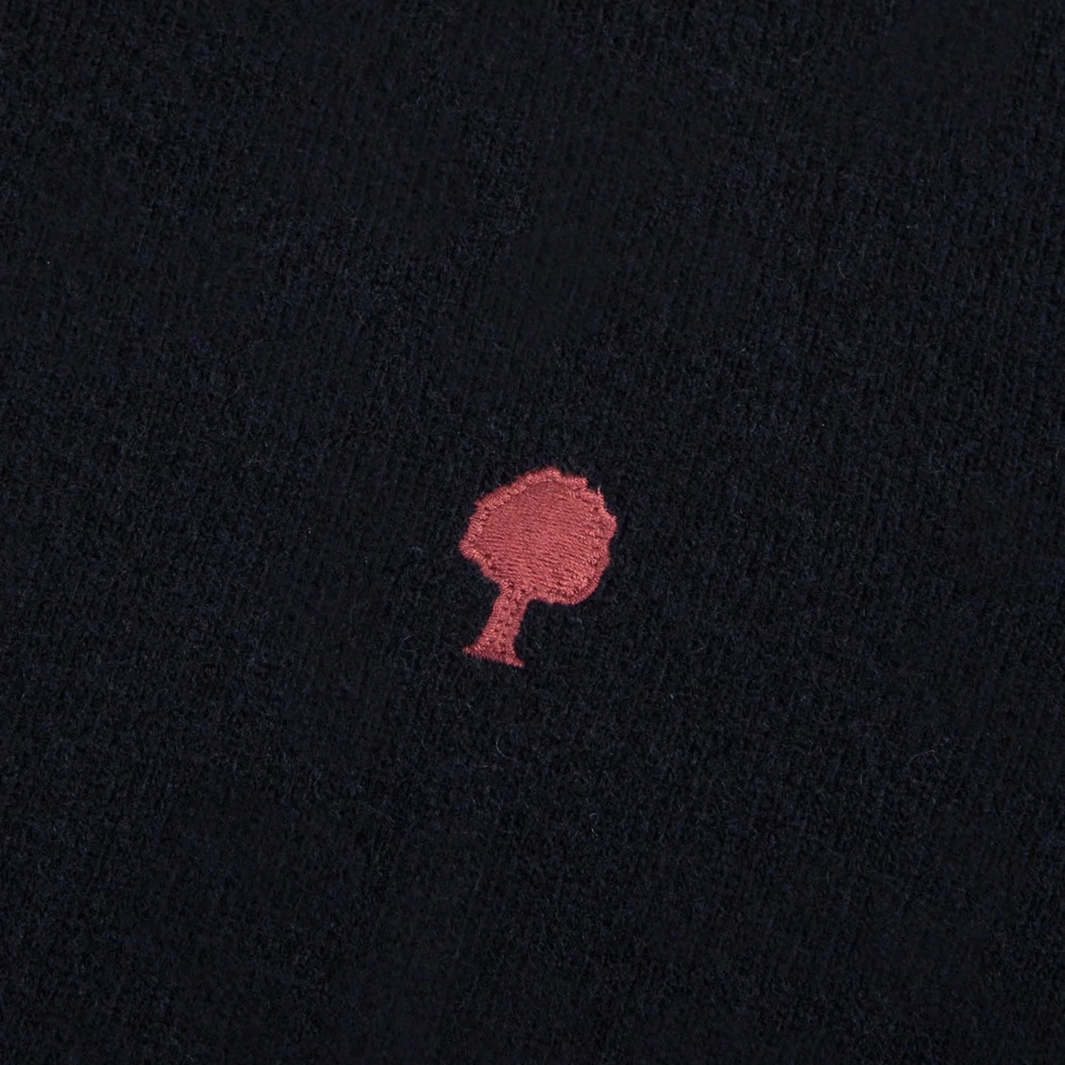 Gros plan de la maille laine bleu marine du pull Marly Faguo et de son arbre brodé rouge