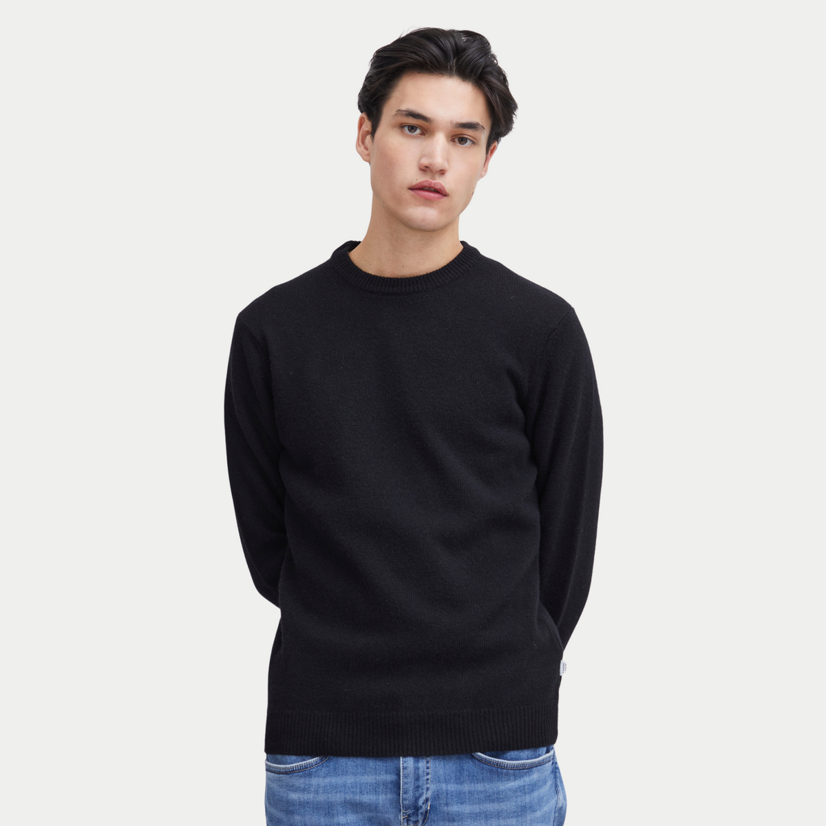 Pull noir Casual Friday porté de face avec un jean bleu délavé, coupe droite en maille fine