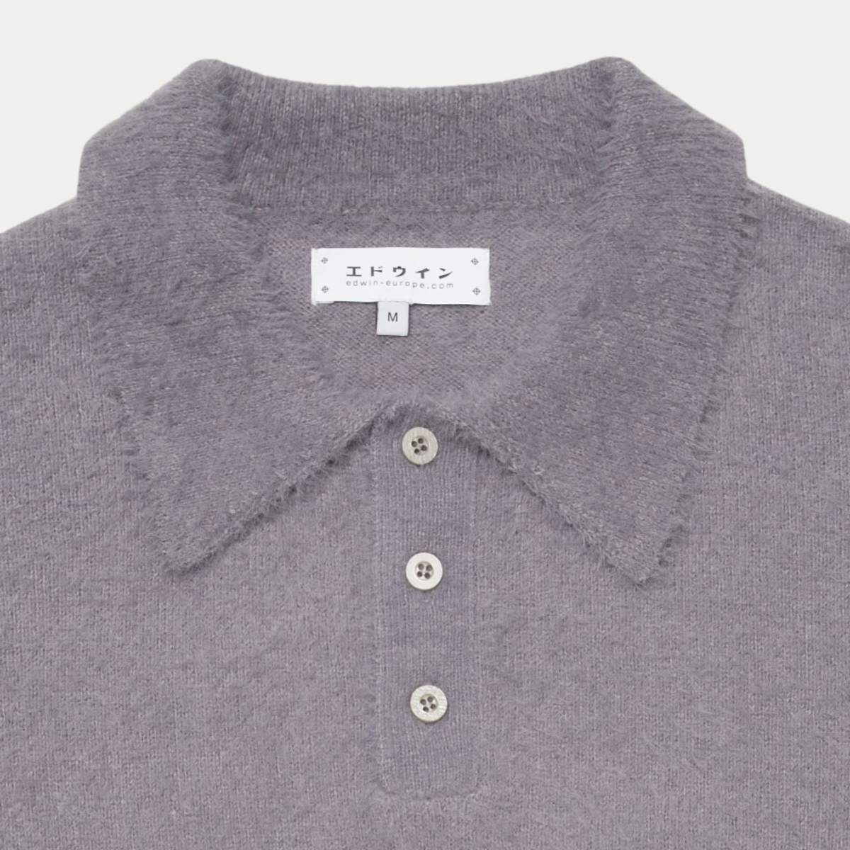 Col polo boutonné du pull Dex Edwin en maille mauve grisé, étiquette de marque Edwin en katakana