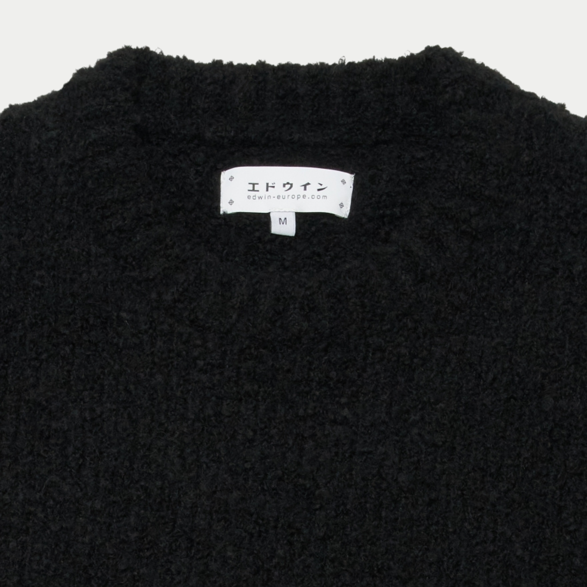Détail du col rond du pull Dun Edwin noir et de son étiquette de marque intérieure