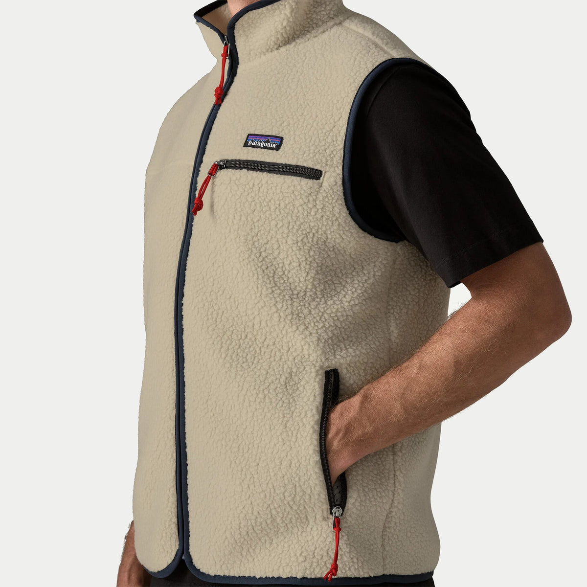 Détail du sherpa bouclé écru du gilet Retro Pile Pelican Patagonia : poche basse zippée, tirette rouge et biais marine