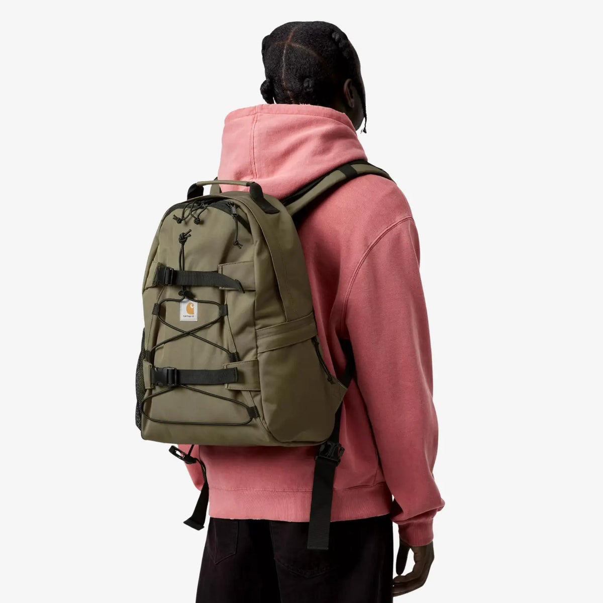 Sac à dos Kickflip kaki clair porté de trois quarts dos, poche en filet latérale et sangle ventrale libre