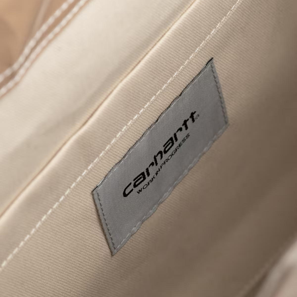 Intérieur du sac en papier Blinkerfluid Carhartt WIP : doublure beige et étiquette grise Carhartt Work In Progress