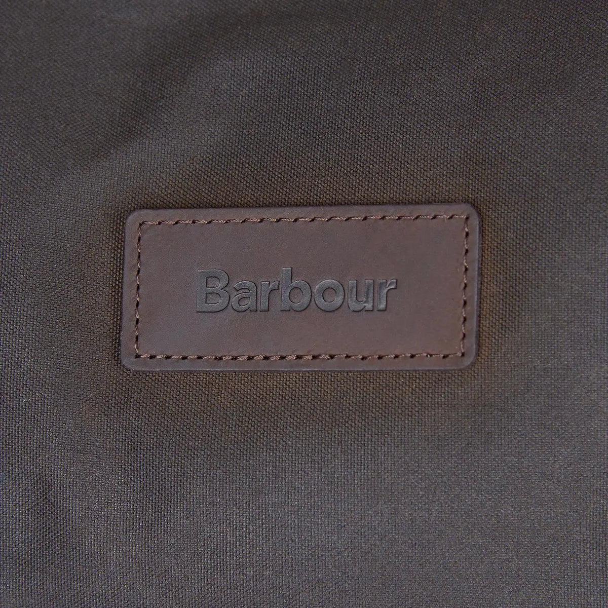 Patch cuir brun estampé cousu sur la toile cirée olive du sac Holdall Wax