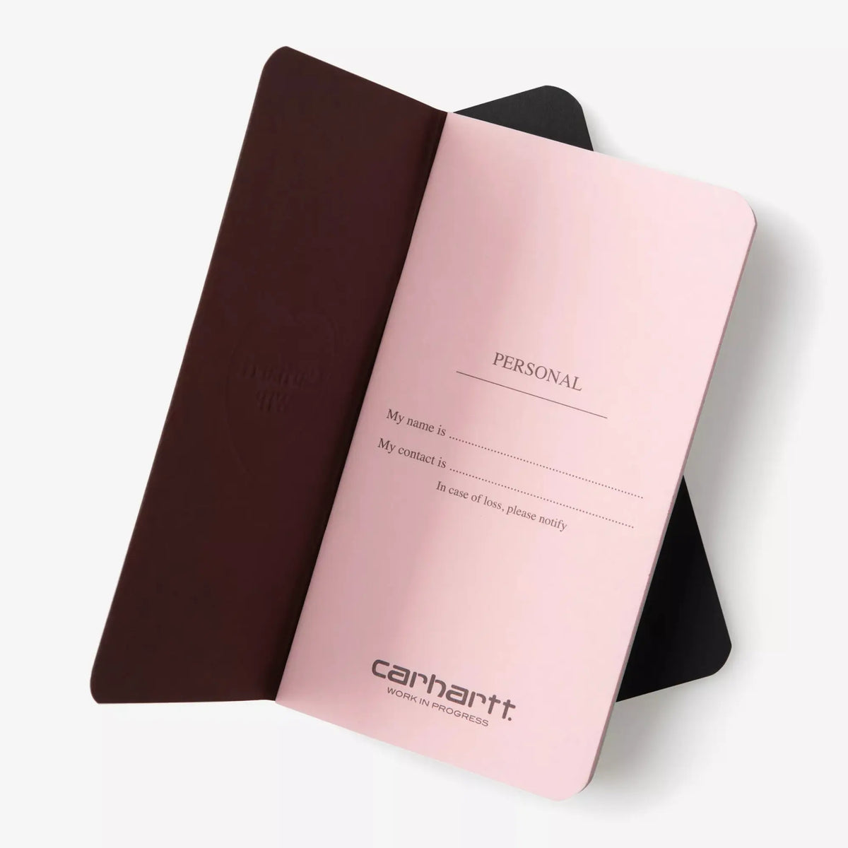 Carnet Heart Pocket Carhartt WIP marron ouvert sur sa page Personal rose, second carnet noir posé dessous