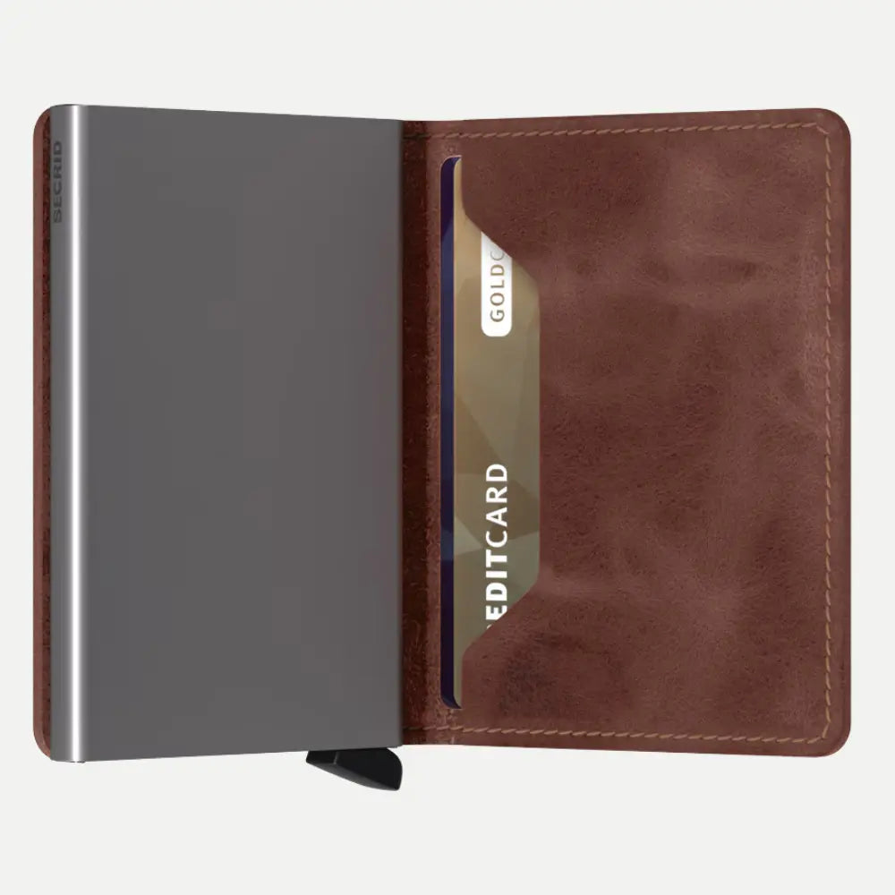 Portefeuille en cuir marron ouvert : boîtier métal brossé à gauche, emplacement carte en cuir à droite