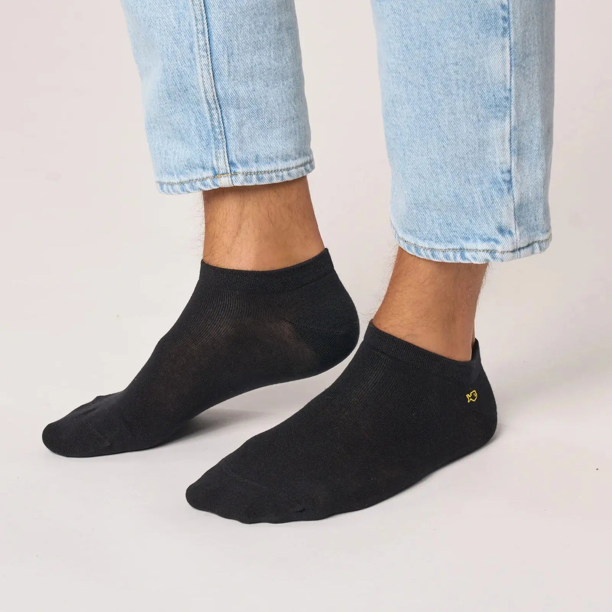 Socquettes noires unies portées avec un jean clair, tige courte qui s'arrête sous la cheville, chevilles nues