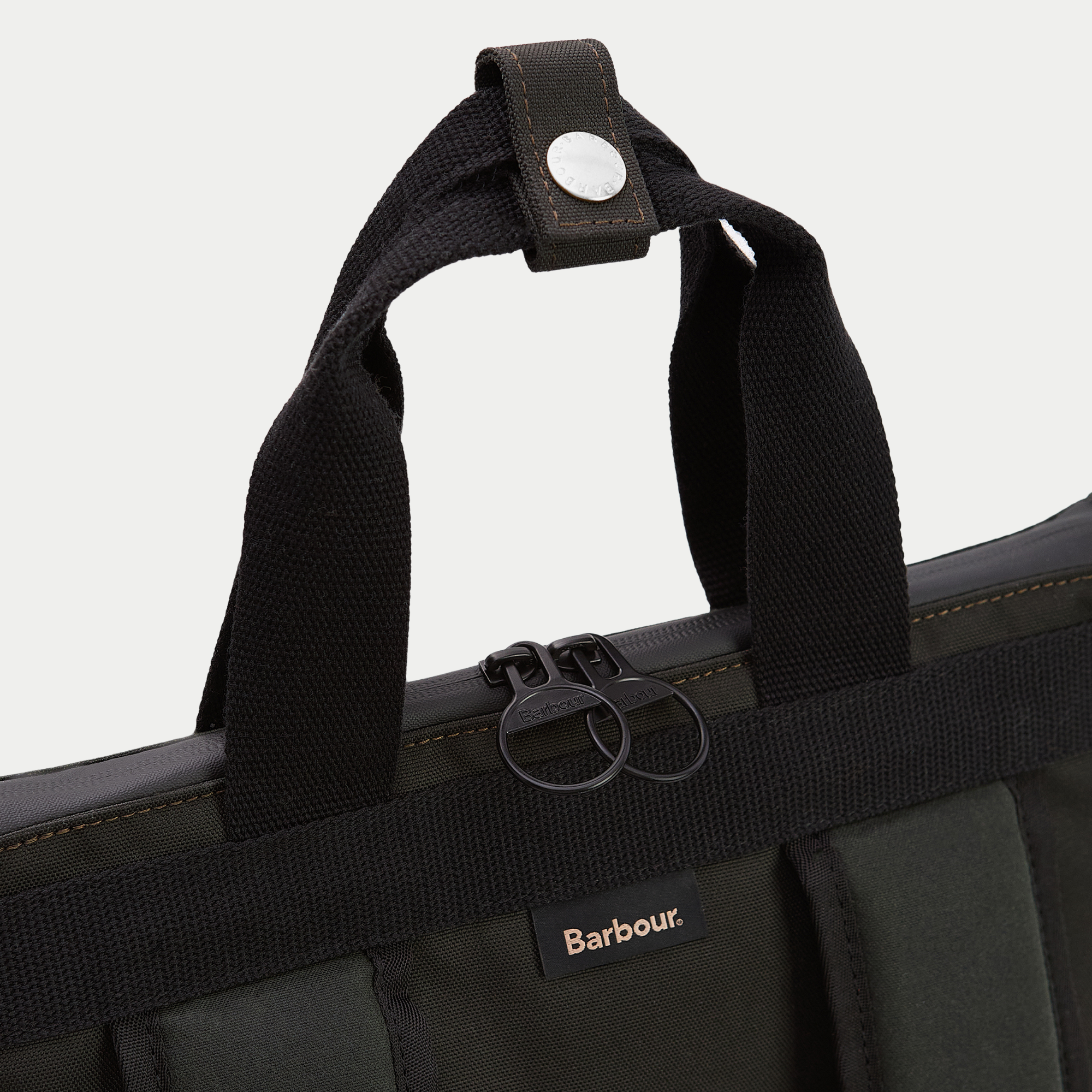 Détail des poignées en sangle du sac à dos Field Wax : passant à pression et double curseur zippé