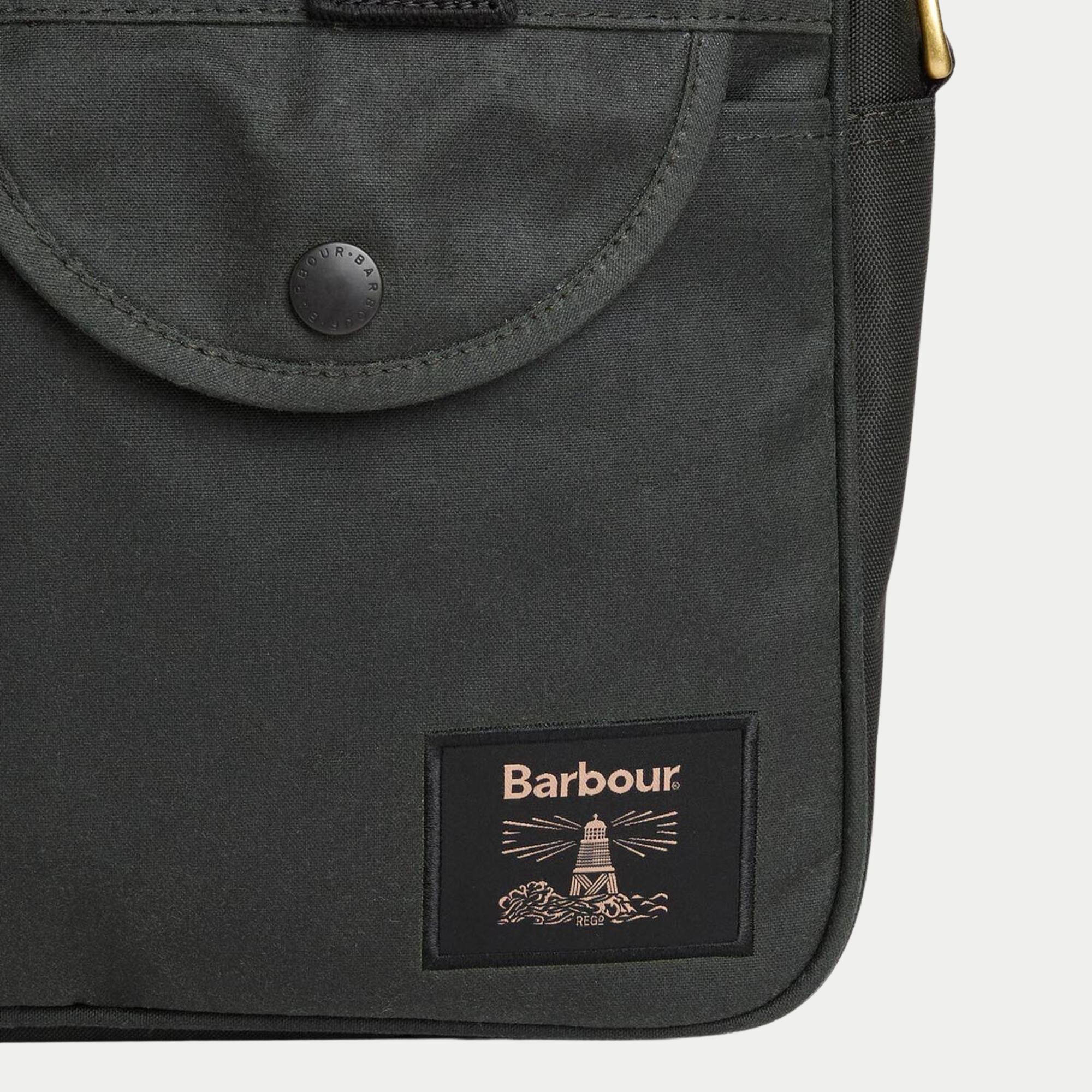 Détail de la poche avant à rabat et bouton-pression Barbour de la sacoche Wax Field Sage, patch phare brodé