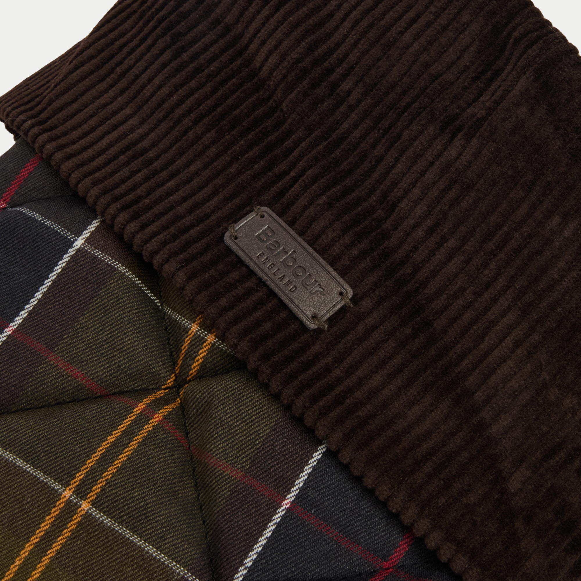 Détail du revers en velours côtelé brun et du badge cuir Barbour England sur la chaussette de Noël tartan olive