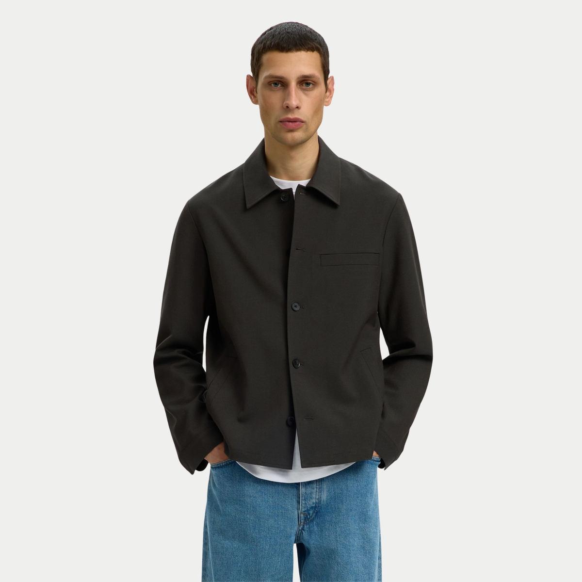 Surchemise Robert Peat Selected Homme portée sur un T-shirt blanc et un jean, mains dans les poches latérales