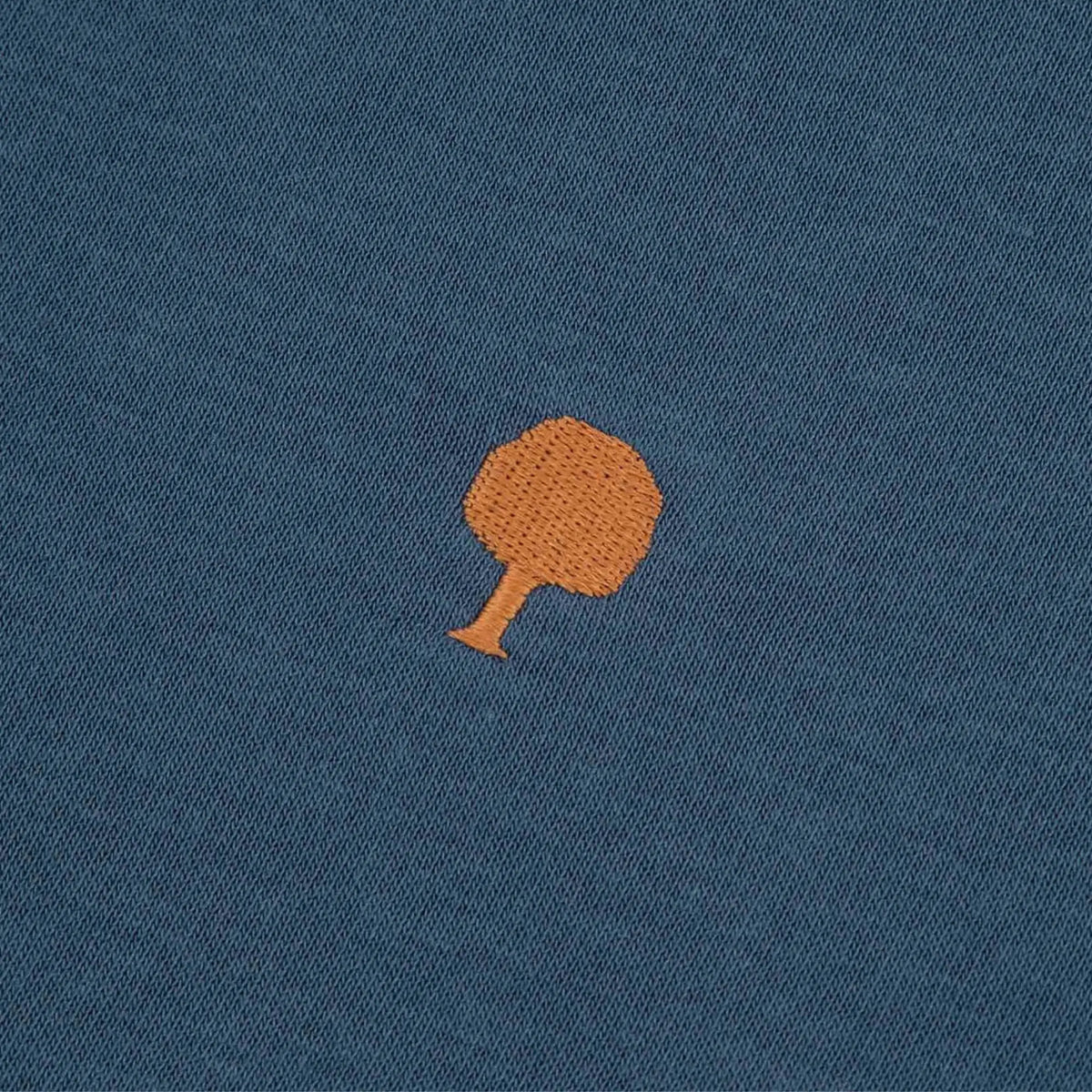 Macro de la broderie arbre orange sur le molleton bleu du Donzy