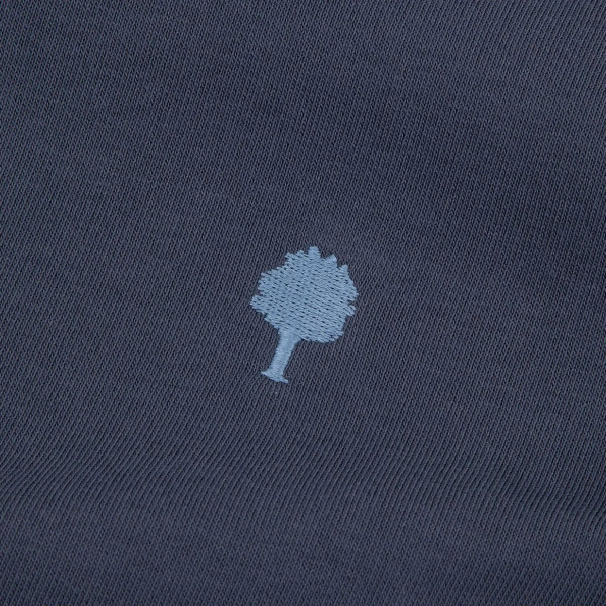 Macro de la broderie arbre bleu ciel sur le molleton bleu marine du Horte