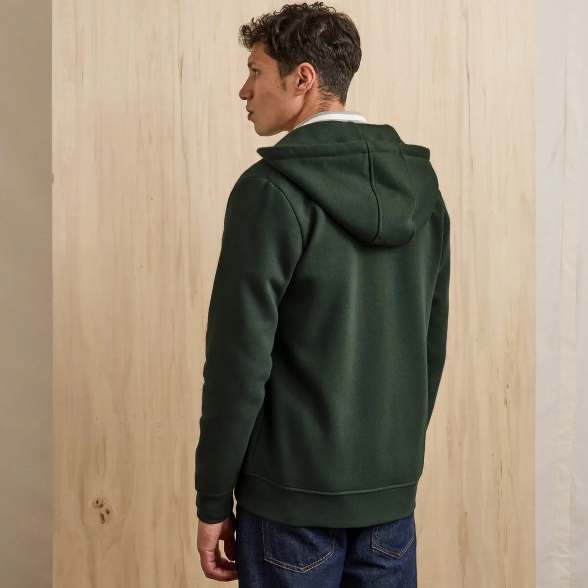 Dos du sweat zippé vert foncé porté, capuche retombant sur les épaules et bord-côte large en bas du dos