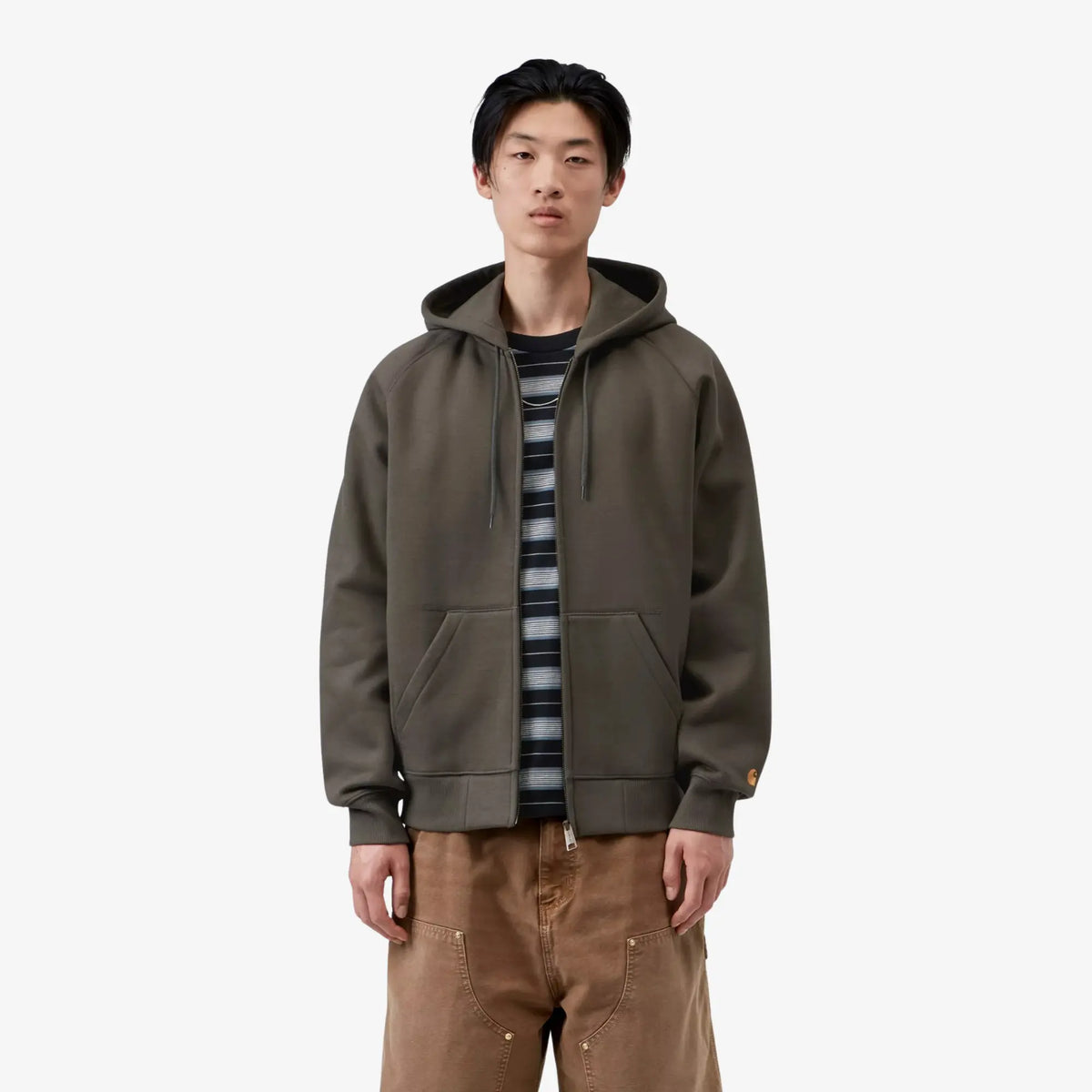 Homme portant le sweat zippé à capuche Chase Carhartt WIP vert olive grisé ouvert sur un t-shirt rayé