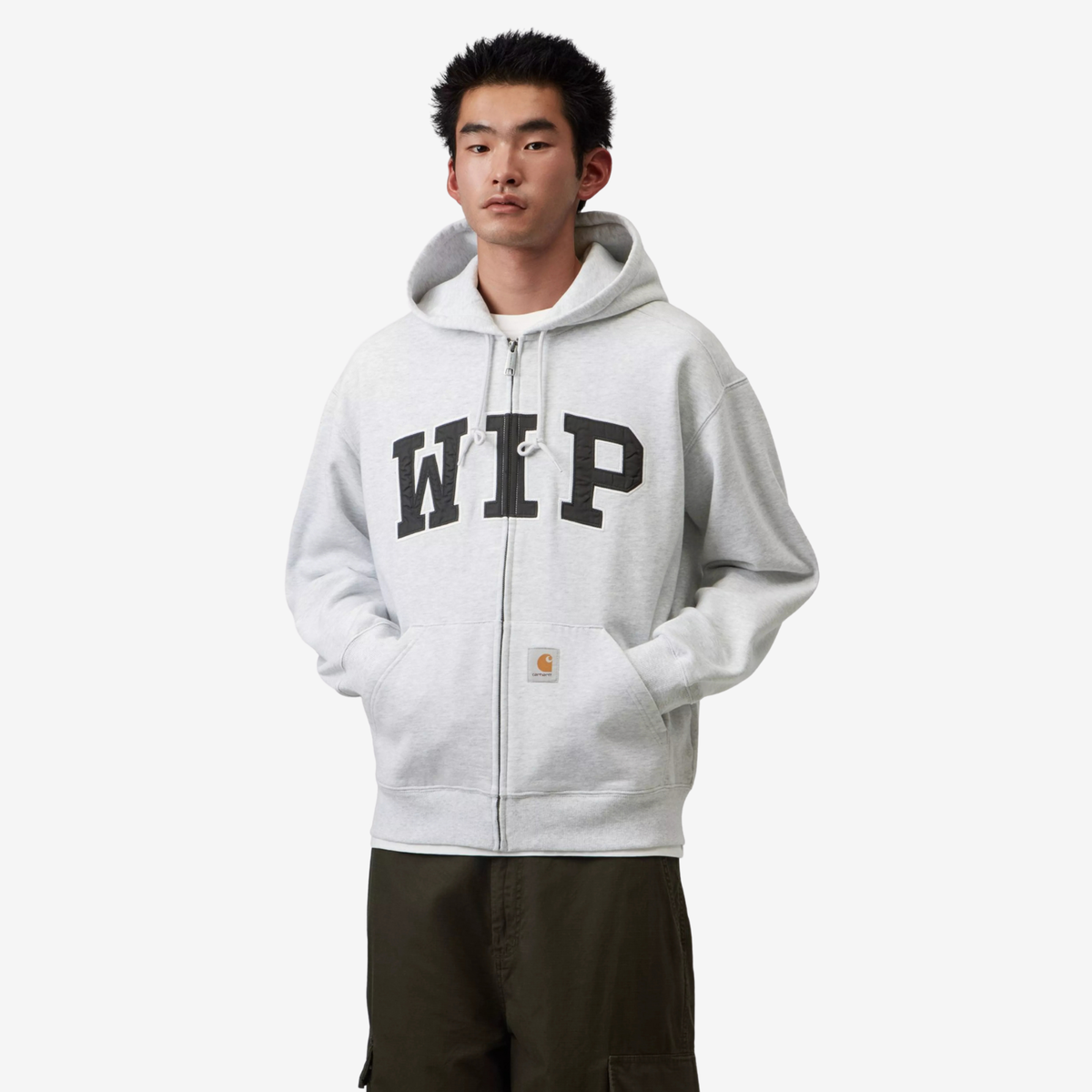 Sweat zippé Carhartt WIP Ash Heather porté fermé, étiquette carrée Carhartt cousue sur la poche kangourou