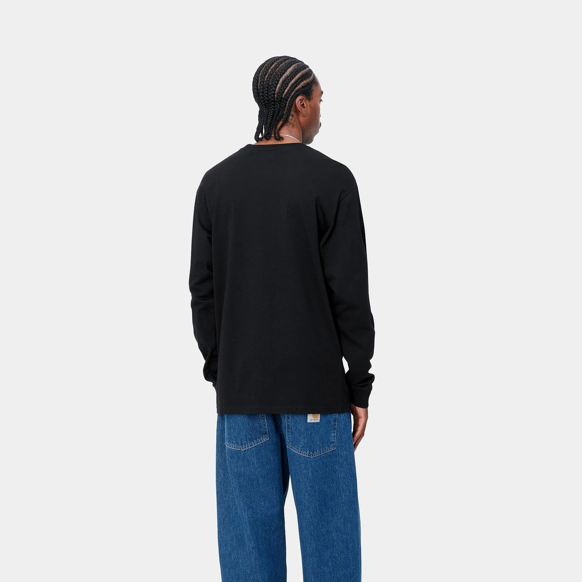 Homme portant le T-shirt manches longues Chase noir Carhartt WIP, vu de dos avec un jean bleu, épaules tombantes