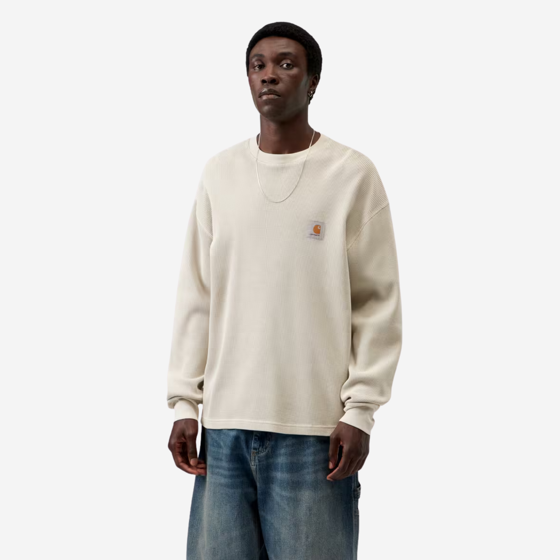 Homme portant le t-shirt manches longues Vista Waffle Carhartt WIP écru, vue de face avec un jean bleu délavé