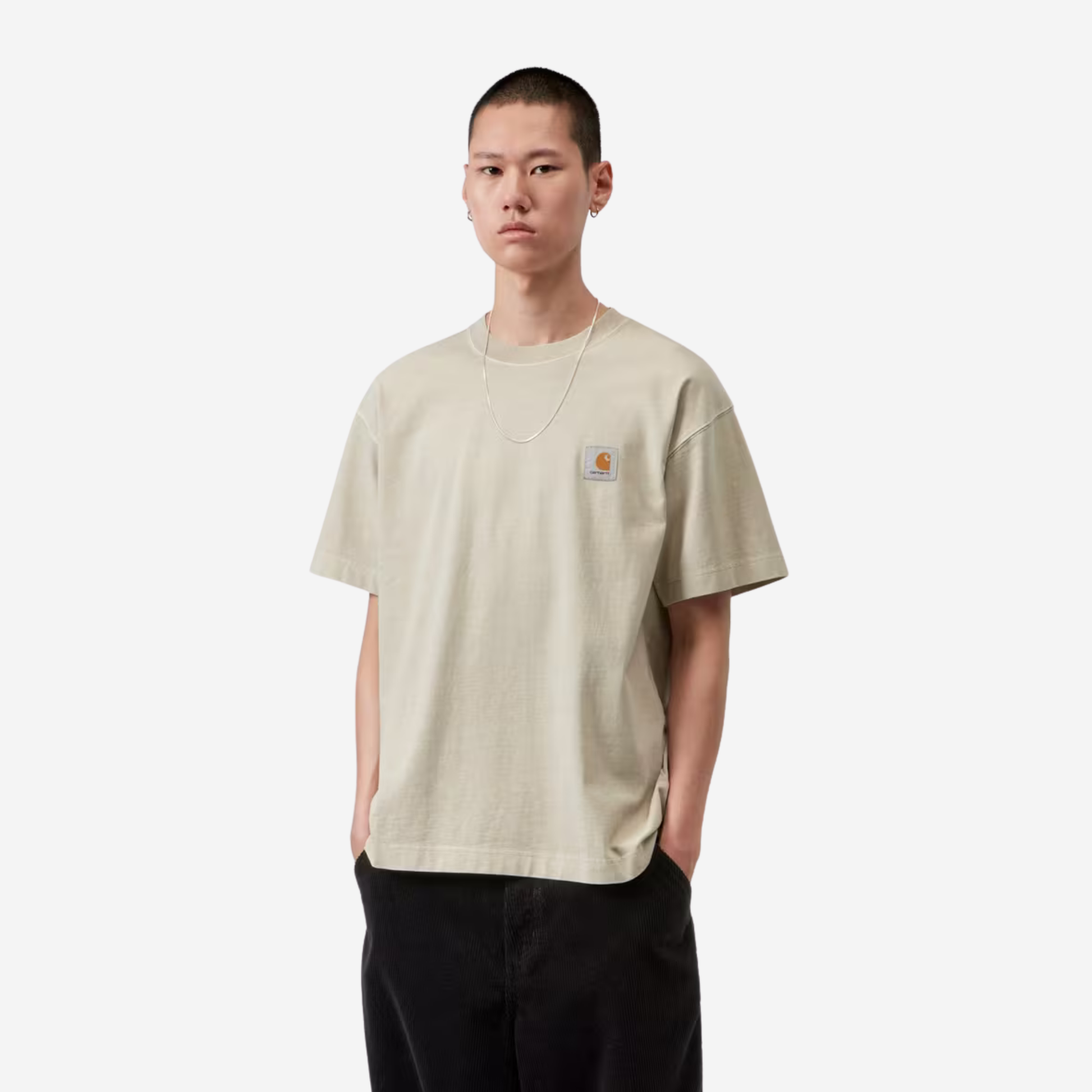 Homme portant le t-shirt Vista Carhartt WIP beige sable, vue de trois quarts face avec un pantalon en velours noir
