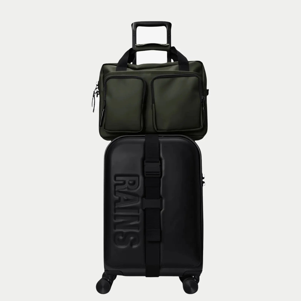 Texel Tech Bag vert kaki posé sur une valise noire, anses passées sur la poignée télescopique