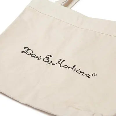 Gros plan du script cursif noir imprimé au dos du tote bag en toile de coton écru