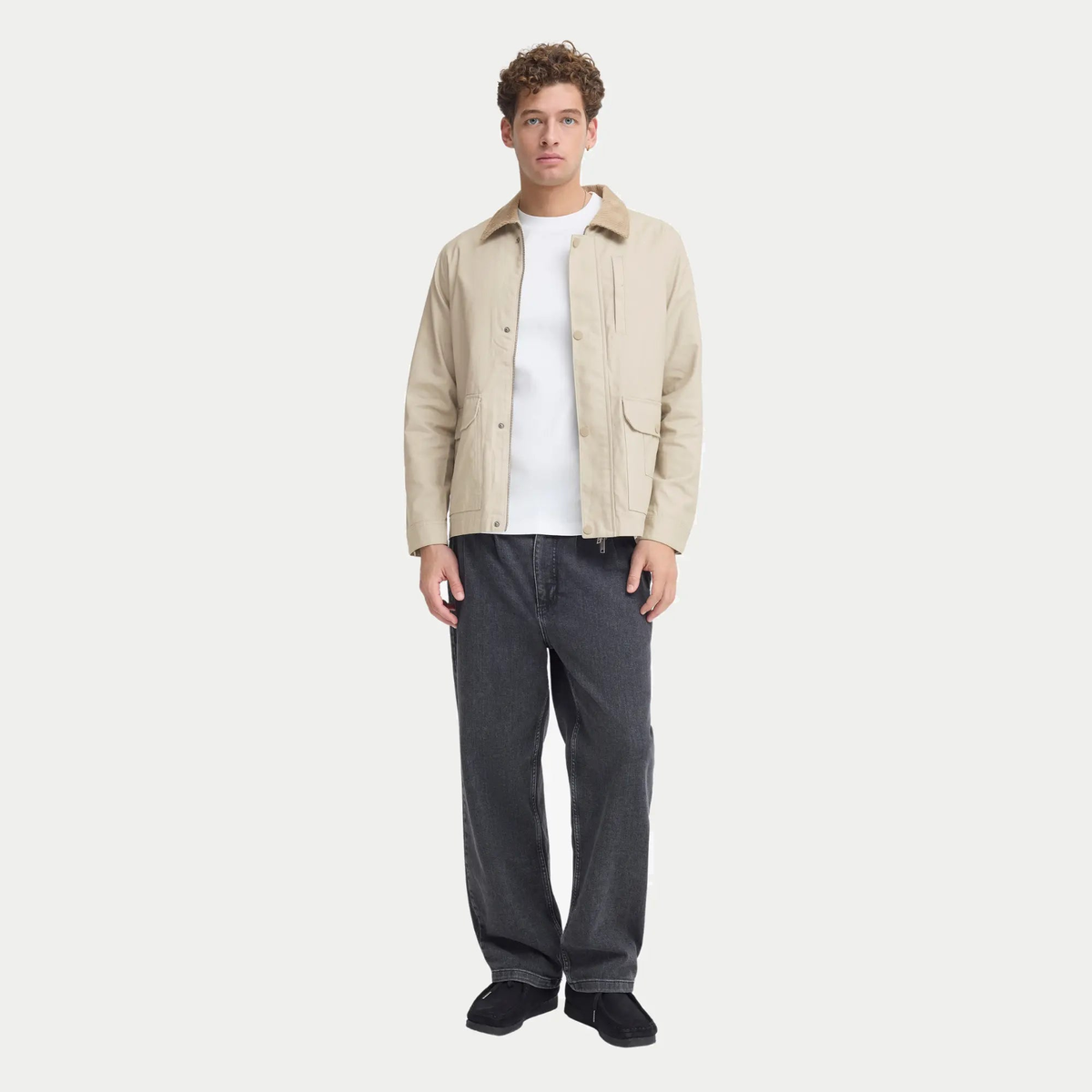 Silhouette complète : veste en coton ciré beige sur un t-shirt blanc et un jean gris