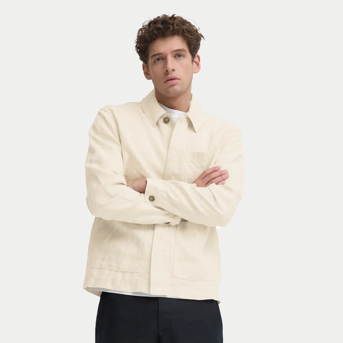 Veste en lin beige naturel portée ouverte sur un t-shirt blanc et un pantalon noir, coupe droite à la hanche