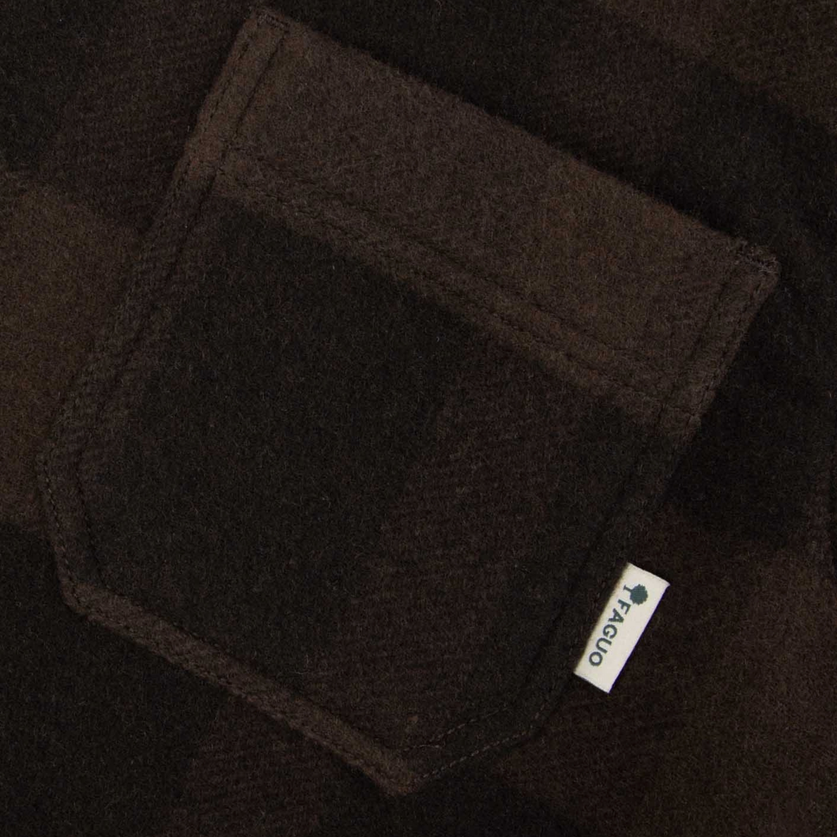 Détail du lainage à carreaux marron et de la poche poitrine à étiquette tissée Faguo