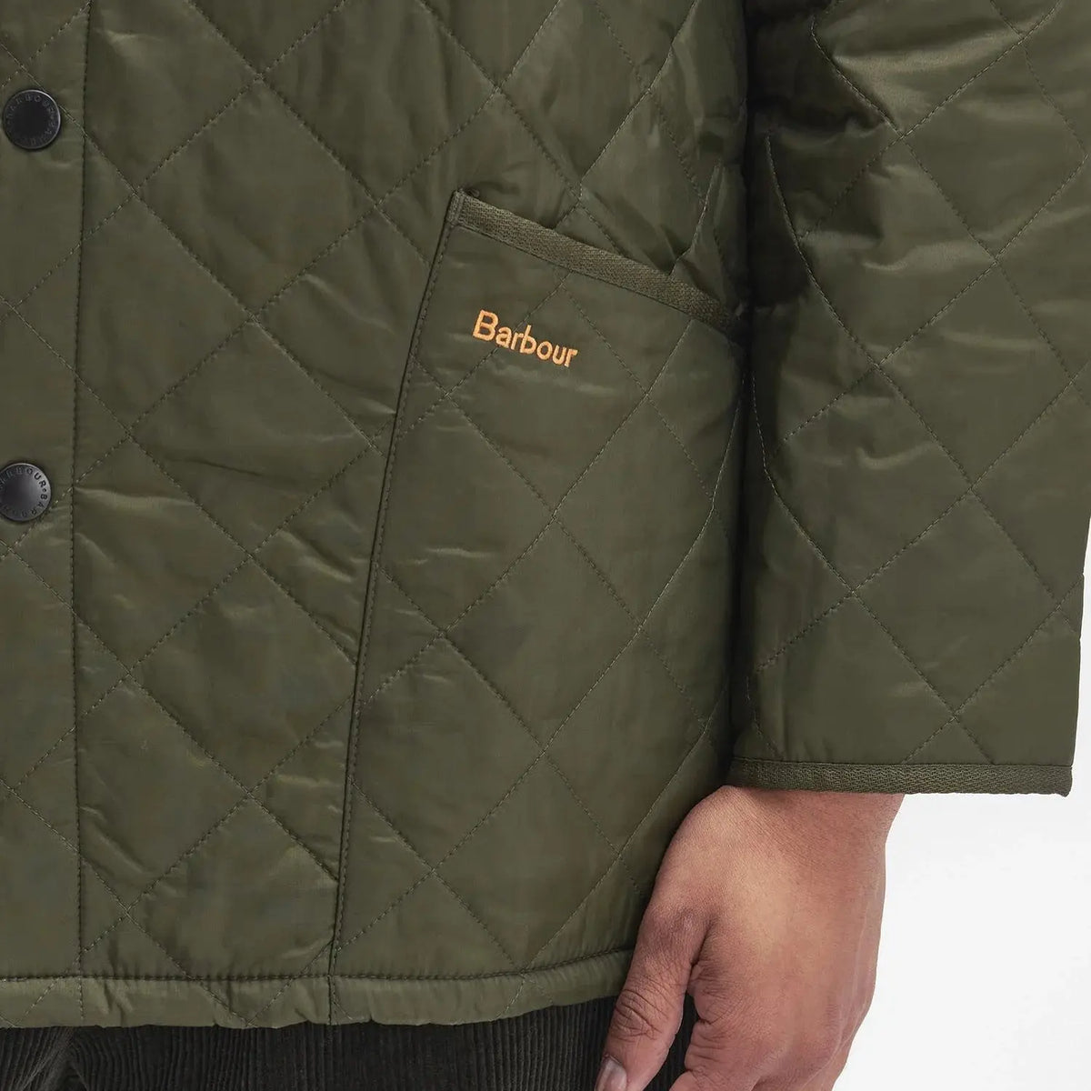Gros plan sur la poche et la broderie Barbour orange de la veste Liddesdale olive, bordure côtelée assortie