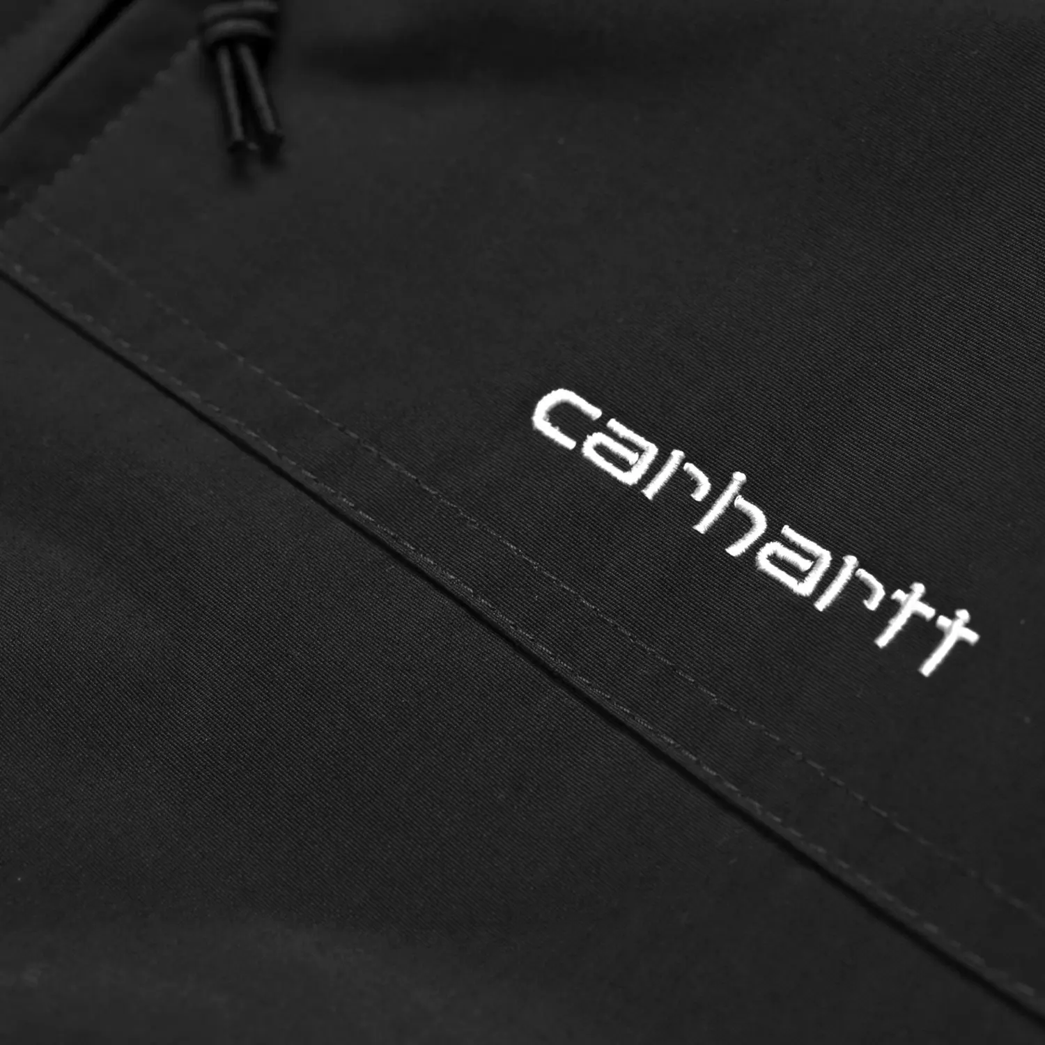 Détail du lettrage Carhartt brodé blanc sur la poitrine de la veste Sail noire
