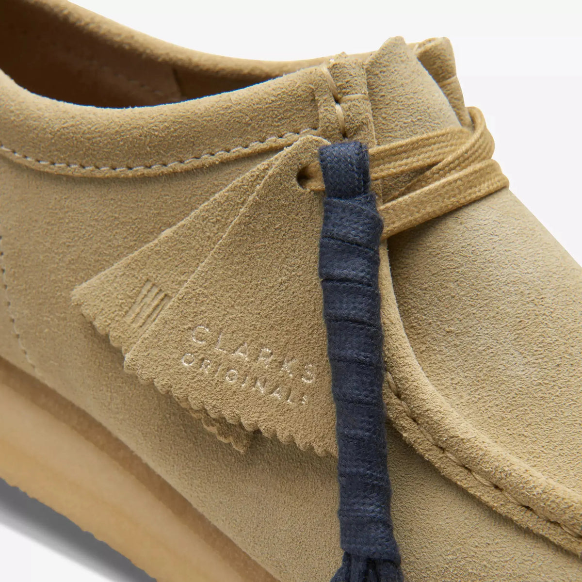 Gros plan de la languette estampée Wallabee Maple et du lacet Bleu Marine fourni