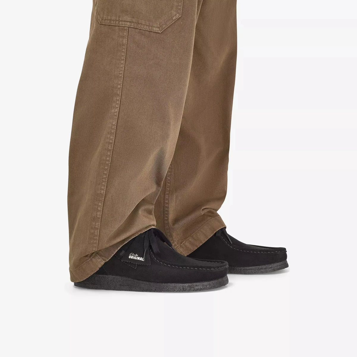 Wallabee noires portées au ras du sol avec un pantalon marron large